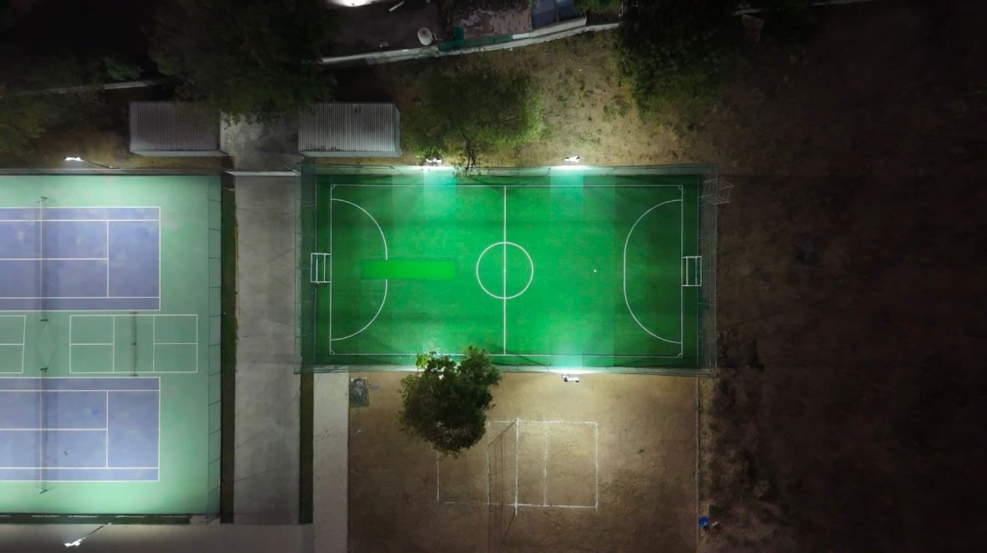 Drona Sports Academy's floodlit courts and turf under lights at night